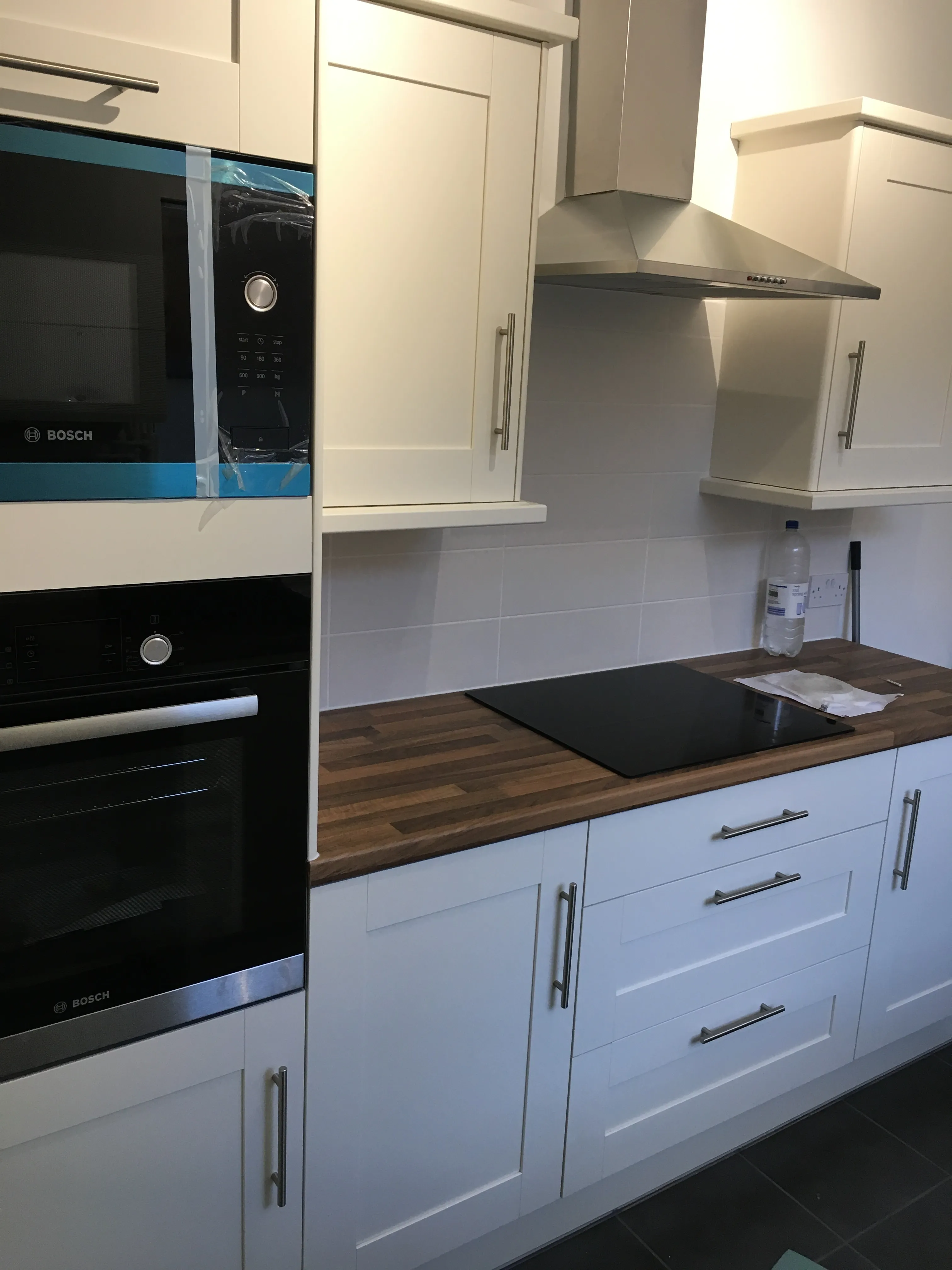 Completed kitchen replacement with white cabinets, integrated appliances and wood-effect worktops