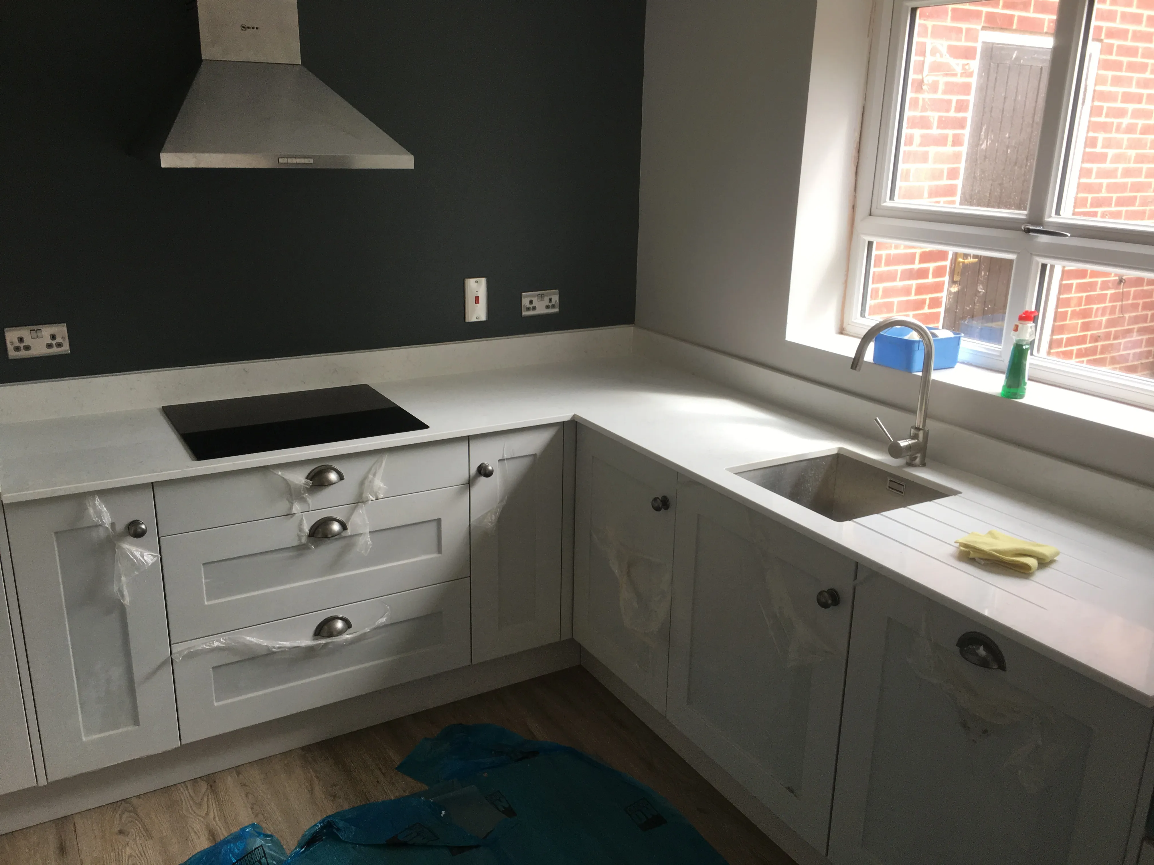 Kitchen installer finishing a landlord kitchen refurbishment with white cabinets and integrated appliances